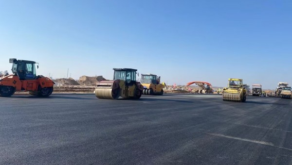 近日，在西部市政建設(shè)集團蘭州新區(qū)城市礦產(chǎn)與表面處理產(chǎn)業(yè)園區(qū)（二期）周邊基礎(chǔ)設(shè)施項目—園區(qū)西路南延段（緯五十路至緯二十八路）項目現(xiàn)場，隨著一輛輛運料車平穩(wěn)駛?cè)耄瑪備仚C將滾燙的瀝青混合料均勻鋪開，標志著項